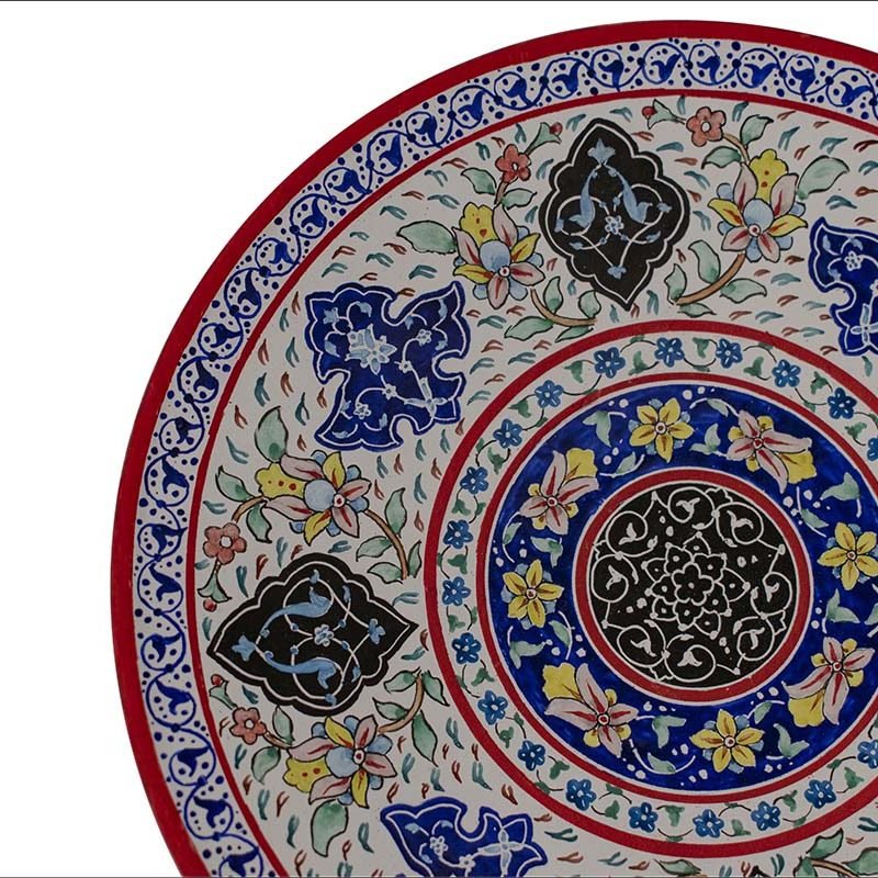 Image of a white enamel plate beautifully adorned with intricate Persian floral motifs in vibrant reds, encapsulating the rich artistry of Isfahani craftsmanship.
