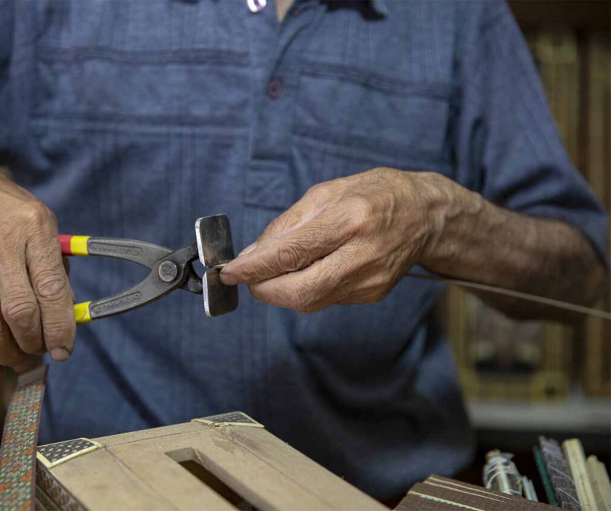A proud Persian craftsman holds his masterpiece, a beautifully crafted wooden backgammon board. Using the intricate marquetry technique, the wooden pieces are inlaid with intricate designs and patterns, showcasing the craftsman's attention to detail and skill in his trade.