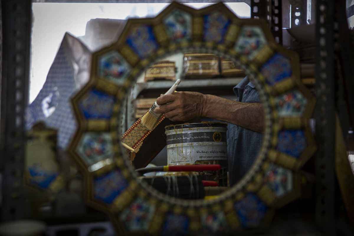 A proud Persian craftsman holds his masterpiece, a beautifully crafted wooden backgammon board. Using the intricate marquetry technique, the wooden pieces are inlaid with intricate designs and patterns, showcasing the craftsman's attention to detail and skill in his trade.