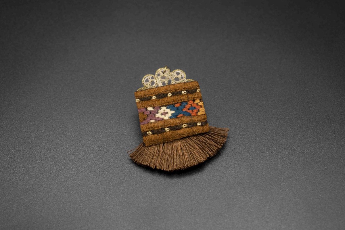 A close-up image of Craftestan's handcrafted Baluchi earrings, featuring intricate embroidery and charming tassels.