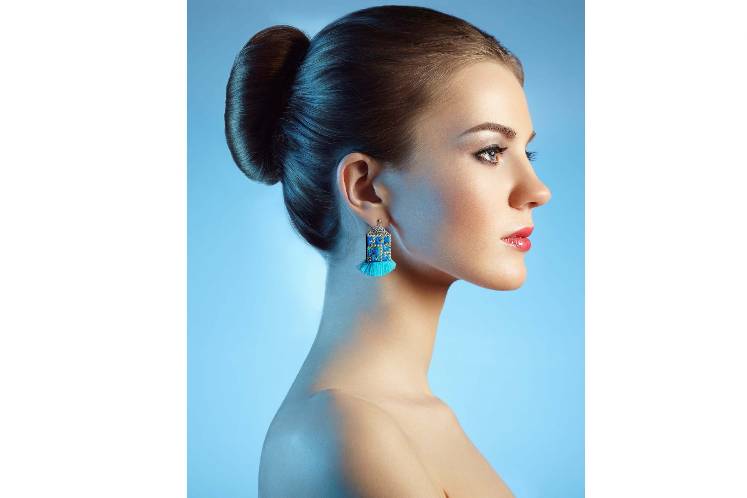 A pair of Bohemian Geometric Baluchi Embroidered Earrings, featuring a blue, yellow, and orange geometric pattern and blue tassels at the bottom.