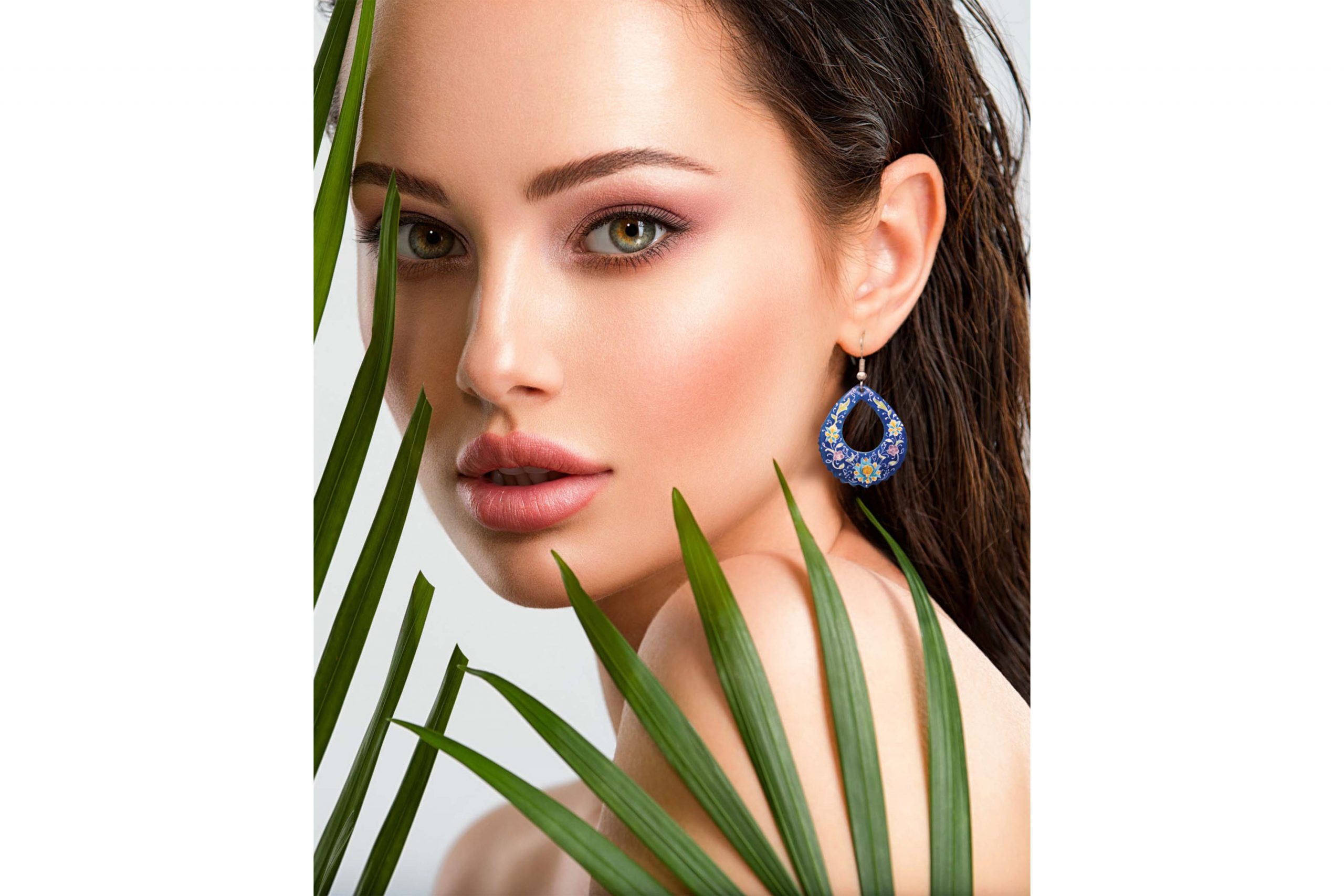 Portrait of a beautiful woman wearing drop eye-shaped Persian enamel earrings with Islimi floral design, hand-painted on enamelled copper body and silver hook.