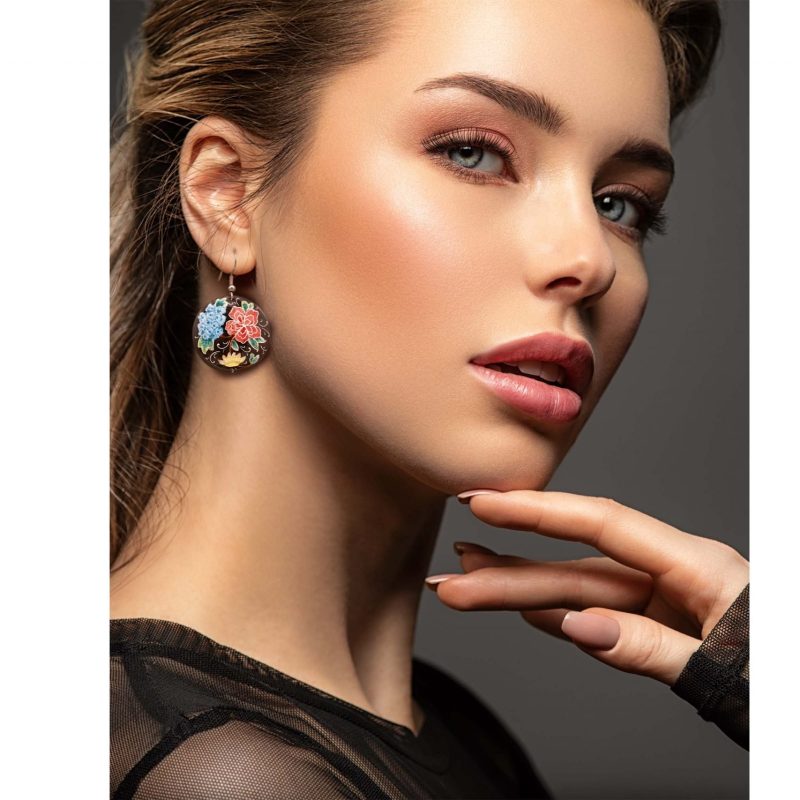 Front view of a beautiful female model wearing Hand-Painted Persian Enamel Watercolour Painting Earrings, featuring a unique Persian garden design in blue, red, and black hues. The earrings are made of enamelled copper with titanium hooks, and each measures 5cm in height and 2.5cm in width.