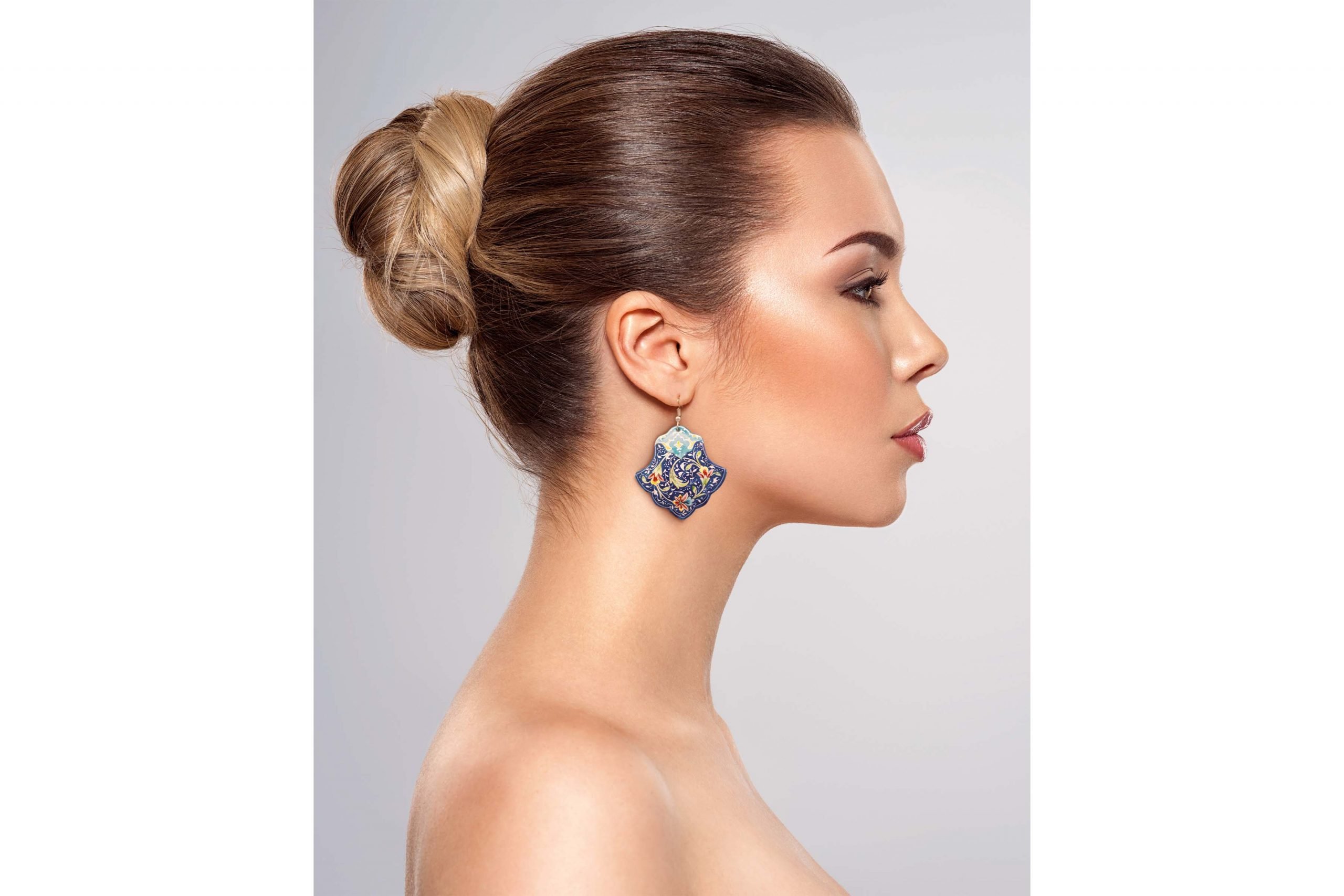 A model wearing Persian enamel watercolour painting earrings with a hand-painted Persian garden pattern. The earrings are made of enamelled copper with a titanium hook.