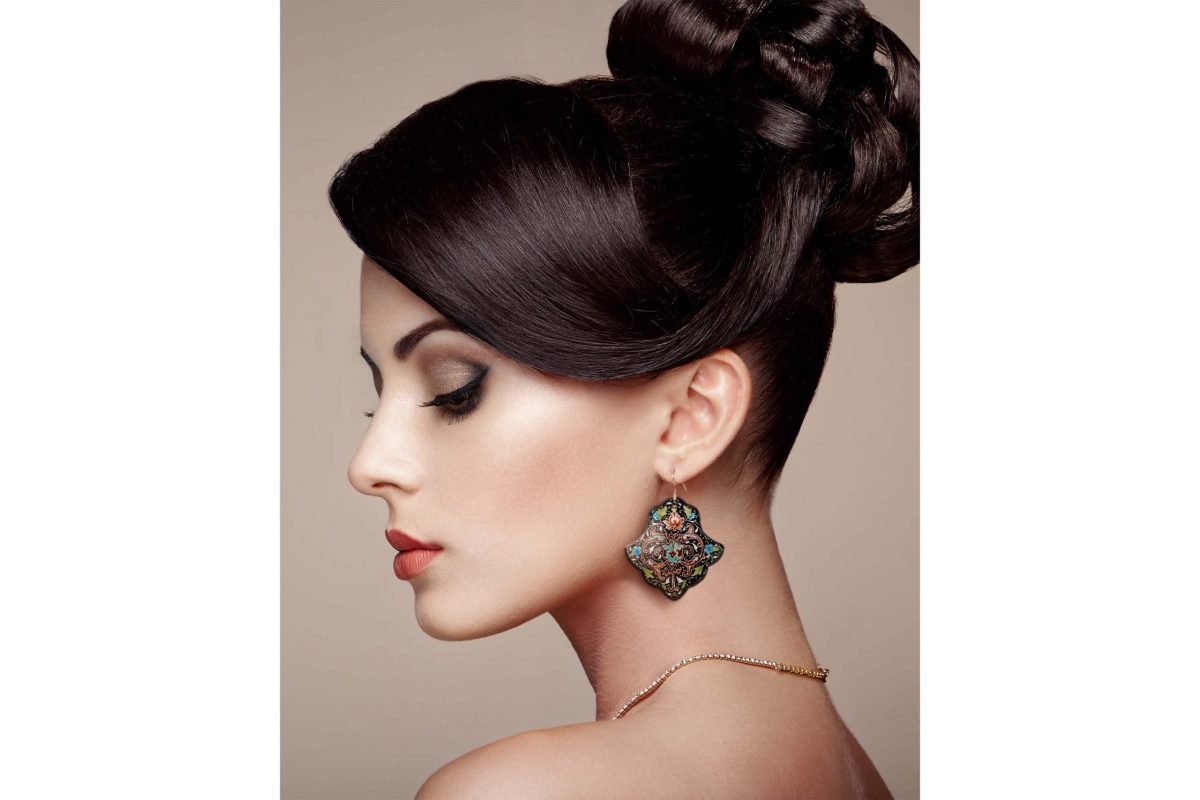Front view of a beautiful female model wearing Hand-Painted Persian Enamel Watercolour Painting Earrings, featuring a unique Persian garden design in blue, red, and black hues. The earrings are made of enamelled copper with titanium hooks, and each measures 5cm in height and 2.5cm in width.