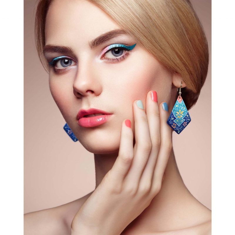 Hand-painted enamel dangle earrings with a floral pattern on a model, made of enamelled copper body and silver hooks.