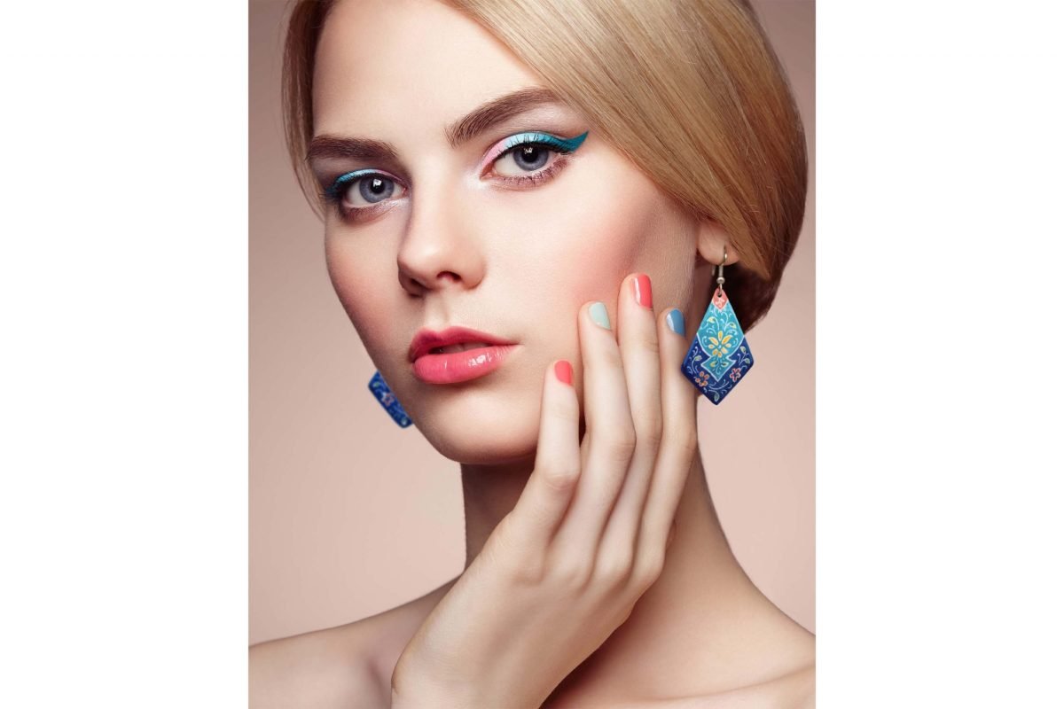 Hand-painted enamel dangle earrings with a floral pattern on a model, made of enamelled copper body and silver hooks.