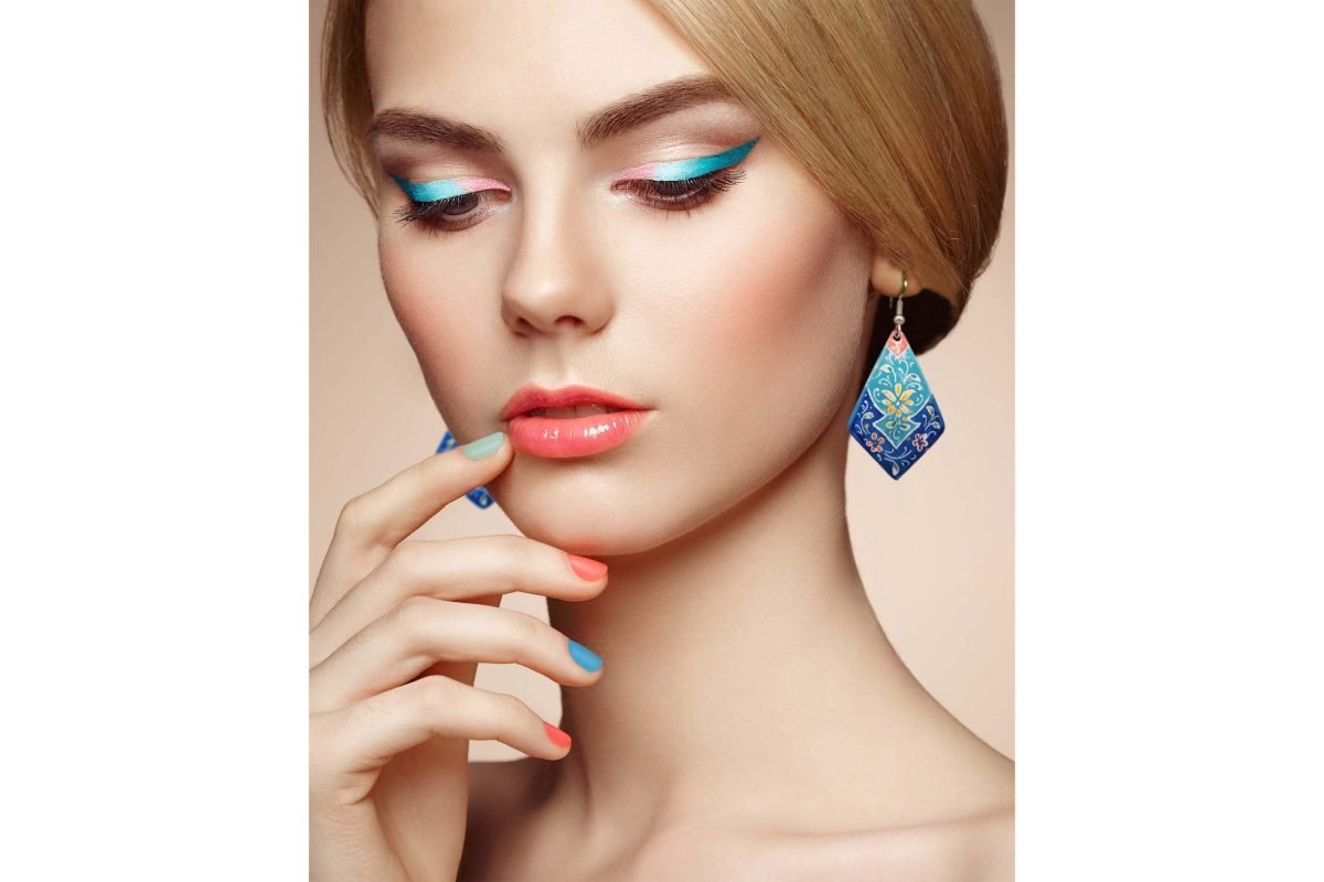 Hand-painted enamel dangle earrings with a floral pattern on a model, made of enamelled copper body and silver hooks.