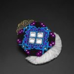 Hand-Embroidered Baluchi Earrings with delicate needlework, mirror embellishments, and white tassels on a neutral background.