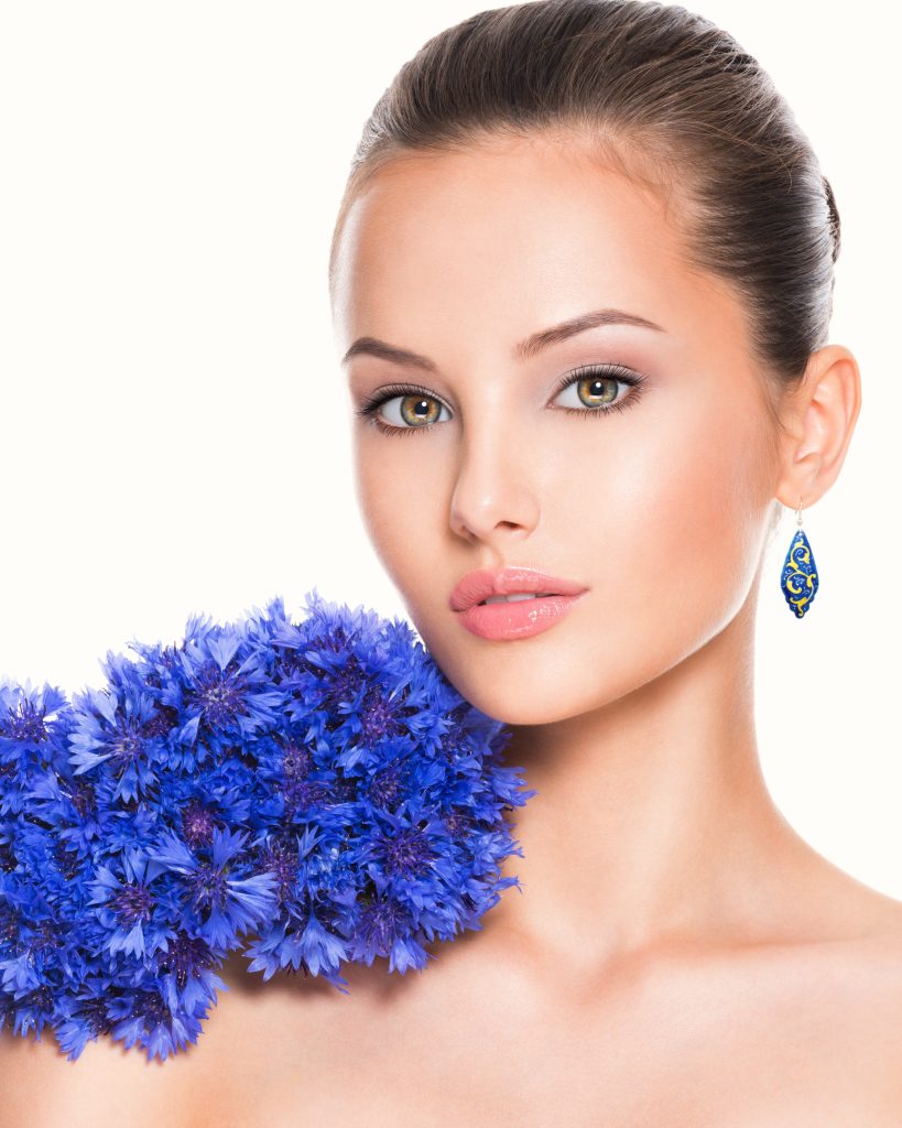 A close-up portrait of a beautiful girl with a Persian enamel earring featuring hand-painted floral designs.