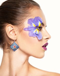 A portrait of a beautiful girl wearing diamond-shaped Persian jewellery featuring breathtaking hand-painted floral and foliate designs in mesmerizing blue, adding a touch of elegance and sophistication to her overall look.