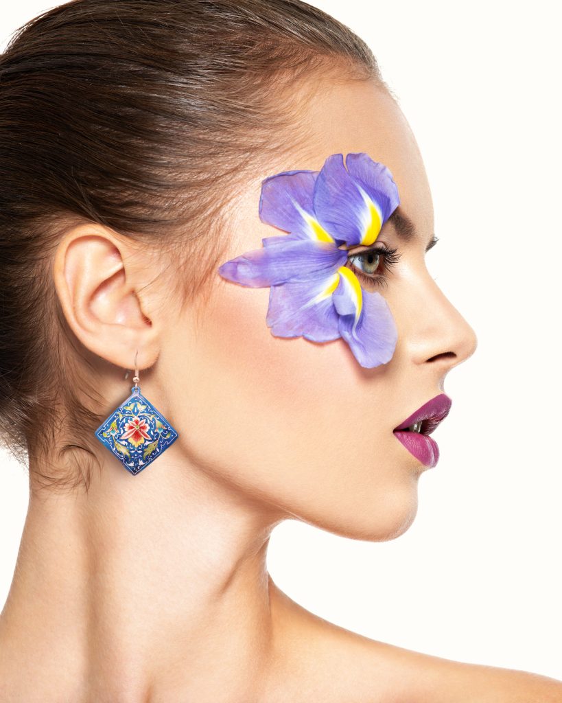 A portrait of a beautiful girl wearing diamond-shaped Persian jewellery featuring breathtaking hand-painted floral and foliate designs in mesmerizing blue, adding a touch of elegance and sophistication to her overall look.