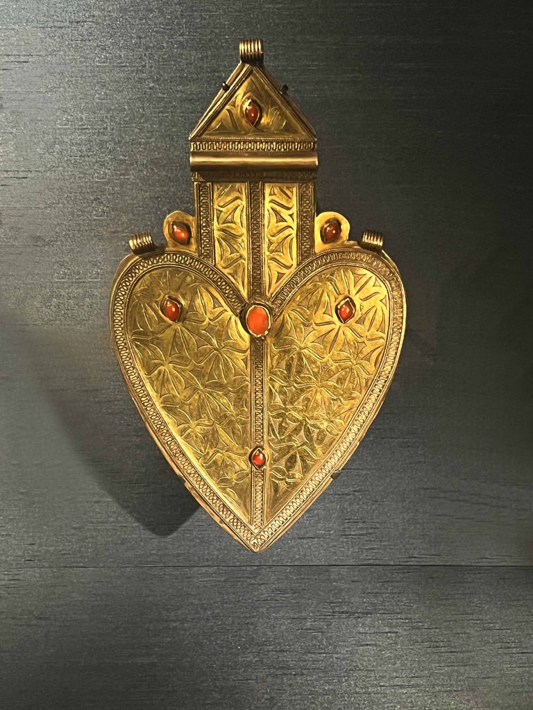 An intricately designed Turkmen pendant on display in the British Museum. Keywords: Turkmen, earrings, cultural heritage, wealth, status, natural world, Silk Road, traditional design, contemporary design, craftsmanship.