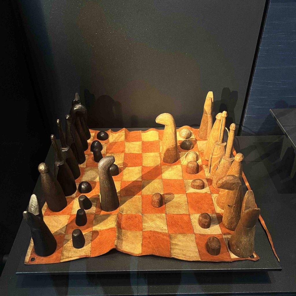 A Nigerian chess board from 1900, currently located in the British Museum. The board features stylized chess pieces that retain characteristics of the game as it was played in the Islamic world. The queen is much less powerful in this version of the game. History of Board Games