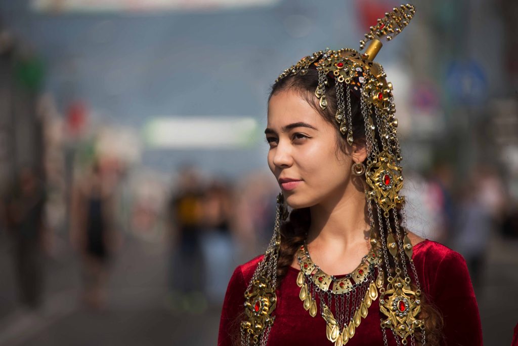 A young girl from Turkmenistan stands wearing a traditional jewellery set that reflects her cultural identity and heritage. The jewellery features intricate designs inspired by nature and cultural symbols, highlighting the skilled craftsmanship of the region. The girl exudes confidence and pride in her culture, and the photo captures the importance of preserving cultural traditions.