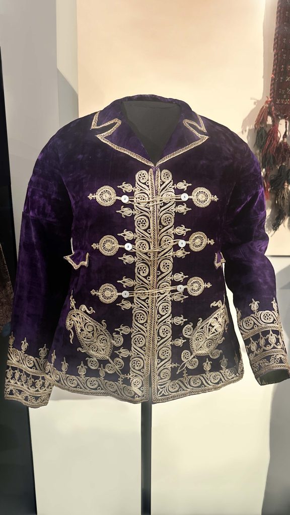 Bridal attire from Persian fashion history featuring a velvet jacket with intricate silver embroidery and a matching green cap from the late Qajar era.