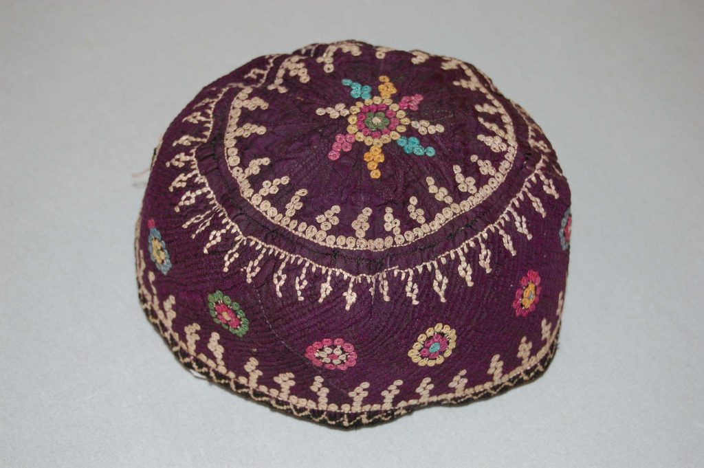 Cap made of deep purple silk, quilted onto cream cotton lining, embroidered with colorful silk threads and trimmed with black and white crochet.