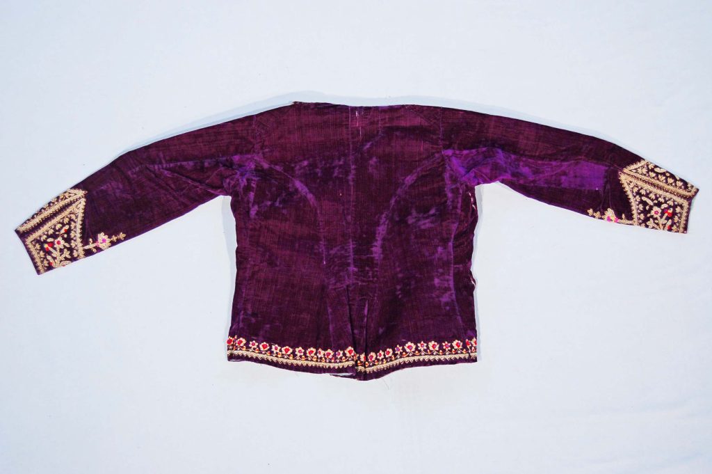 Purple velvet jacket lined with light green glazed cotton, featuring metal thread embroidery and colorful woolen bobbles. Persian fashion history.