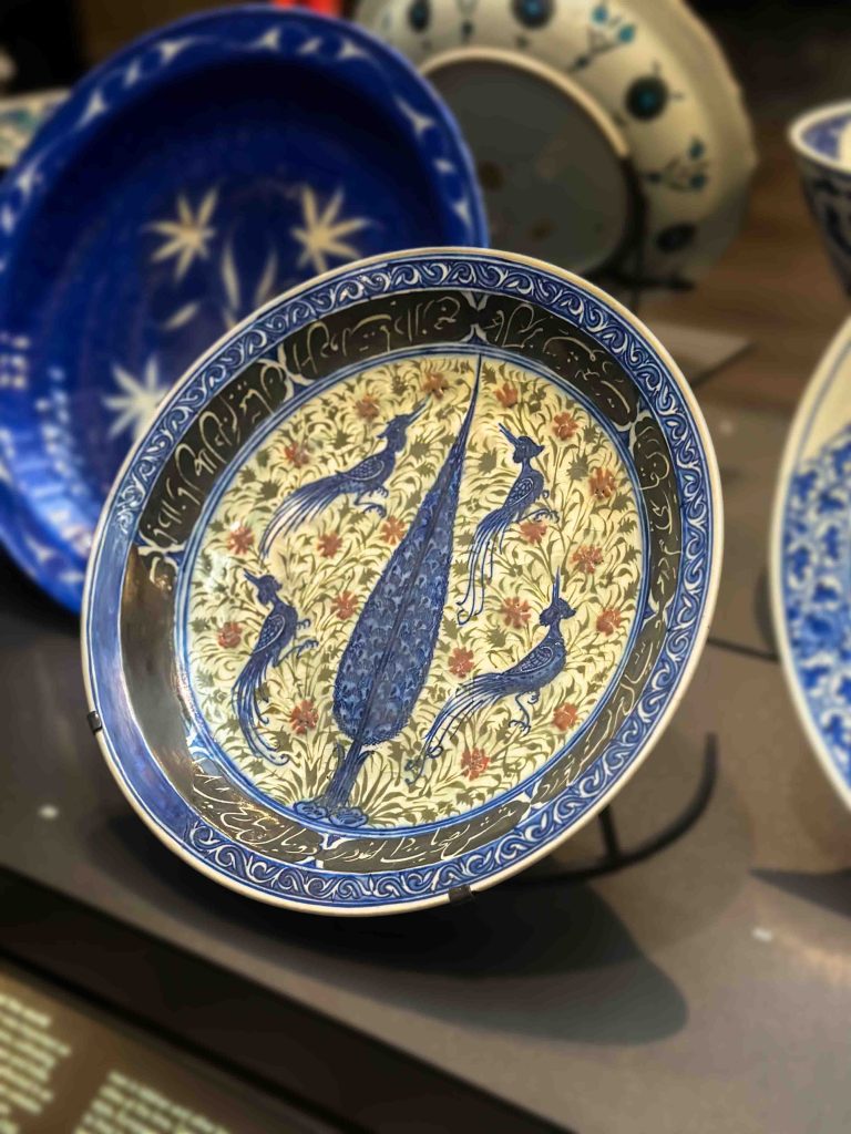 A stunning Safavid Khata'i Persian Art dish with underglaze black and blue paintings, depicting a cypress tree, pheasants, and a Persian inscription, crafted from stonepaste. Khata'i Persian Art