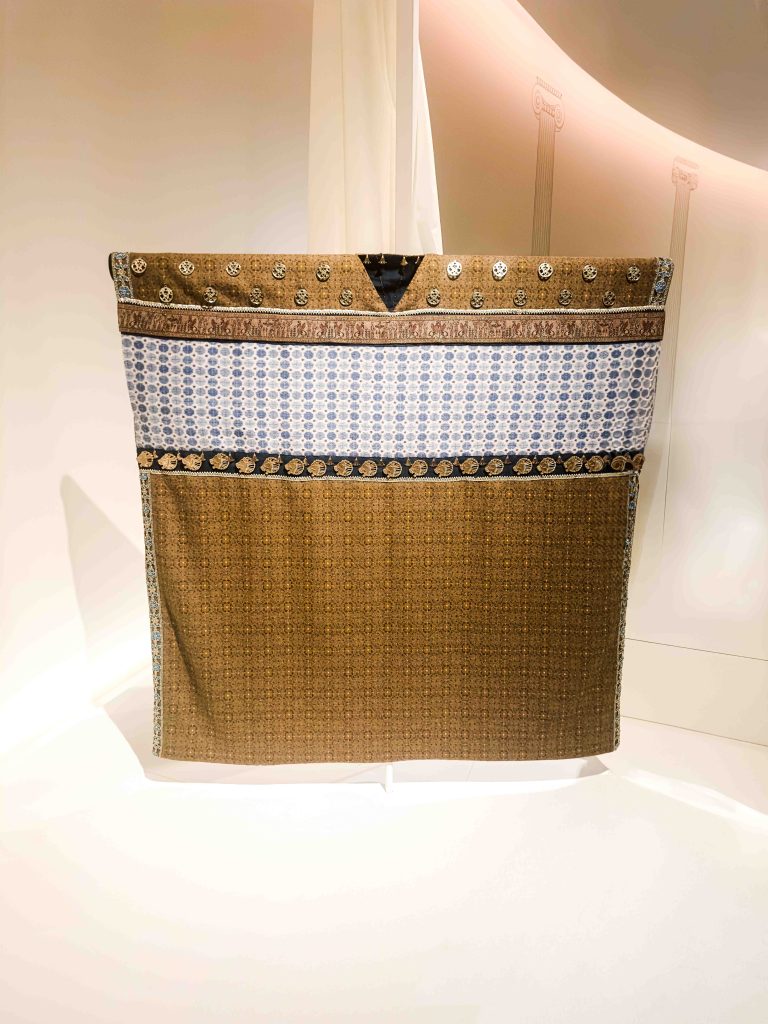 An image of the meticulously recreated Achaemenid royal costume, adorned with intricate metallic embroidery and gold-painted resin appliqués on luxurious lamb's wool, offering a tangible glimpse into the magnificence of ancient Persian court attire. An example of luxury Persian clothing. Ancient Persian Clothing