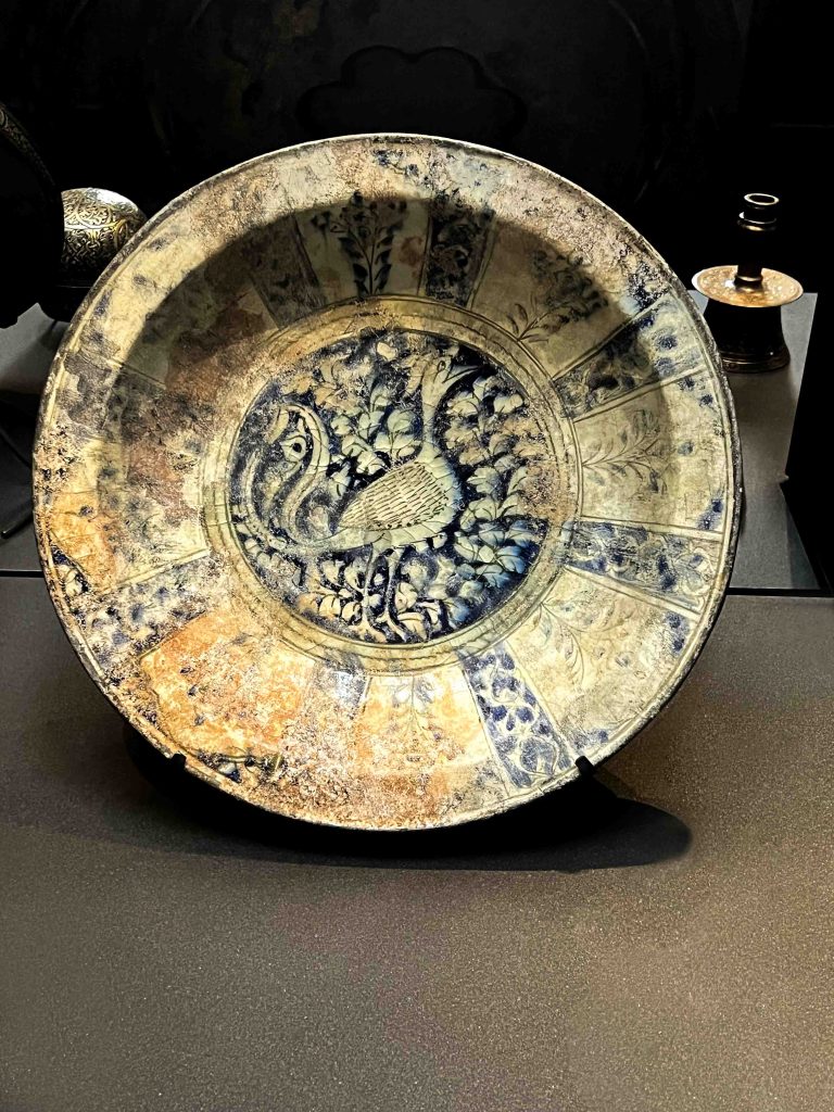A remarkable Khata'i dish from the Ilkhanid dynasty, featuring underglaze black, blue, and turquoise paintings, including a chinoiserie bird within a panelled border. Khata'i Persian Art