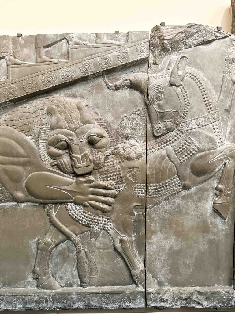Nineteenth-century plaster cast depicting a bull and lion scene, inspired by sculptures from the Palace of Darius at Persepolis, suggesting various symbolic interpretations.