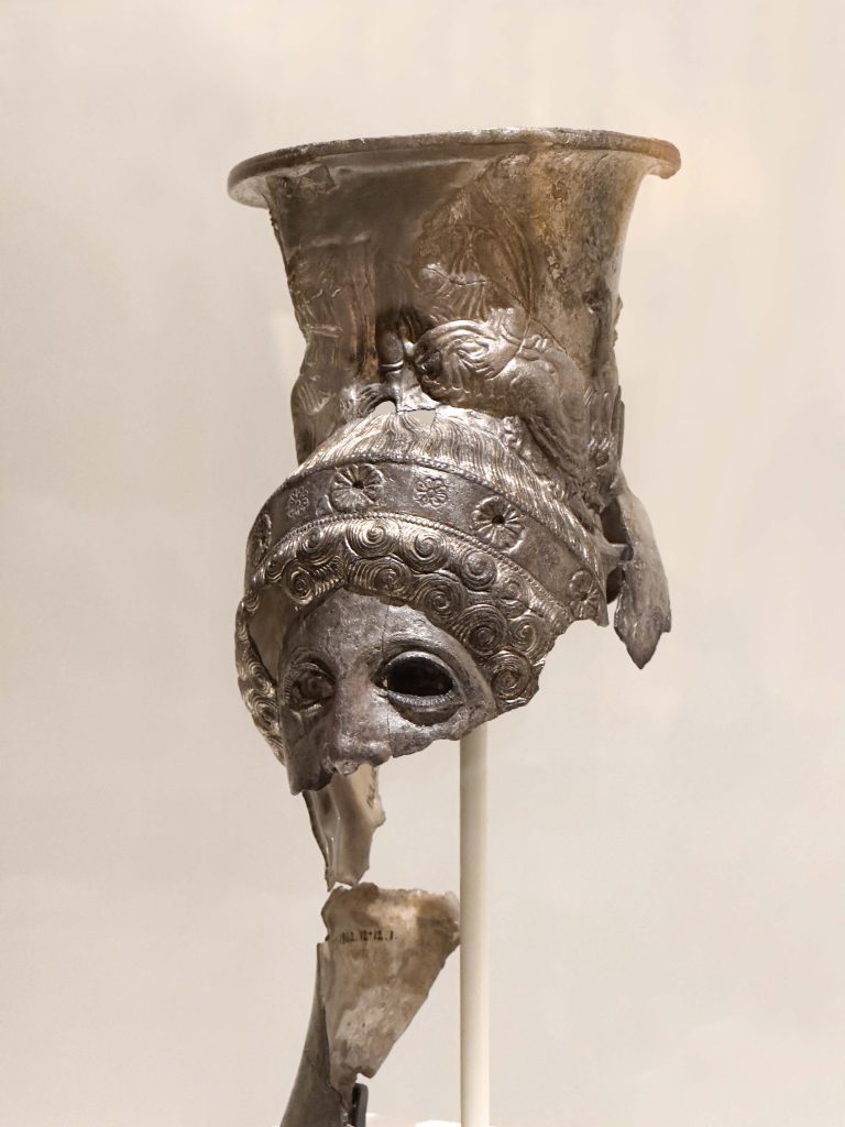 A meticulously crafted Lycian Drinking Cup showcasing the fusion of Persian elegance and Greek artistry, rich with multicultural narratives, detailed repousse decoration, and gilded panels, symbolizing the convergence of diverse cultures in the realm of luxury