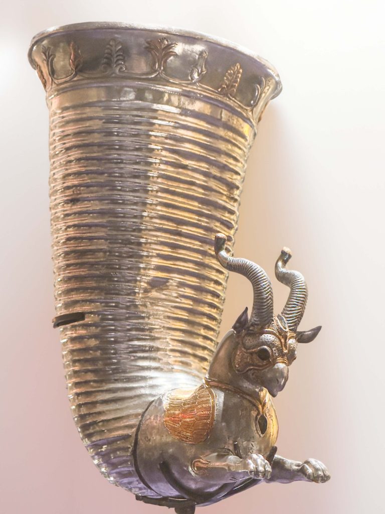 Achaemenid gilt silver rhyton showcasing a horned winged griffin, palmettes, and lotus-buds detailing, representing the elegance of Persian drinks.