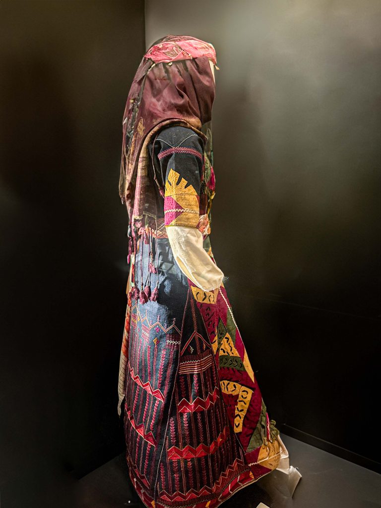 A detailed Galilean jillayeh showcasing intricate embroidery patterns and vivid silk patches, emblematic of Arabian clothing and Palestinian identity.