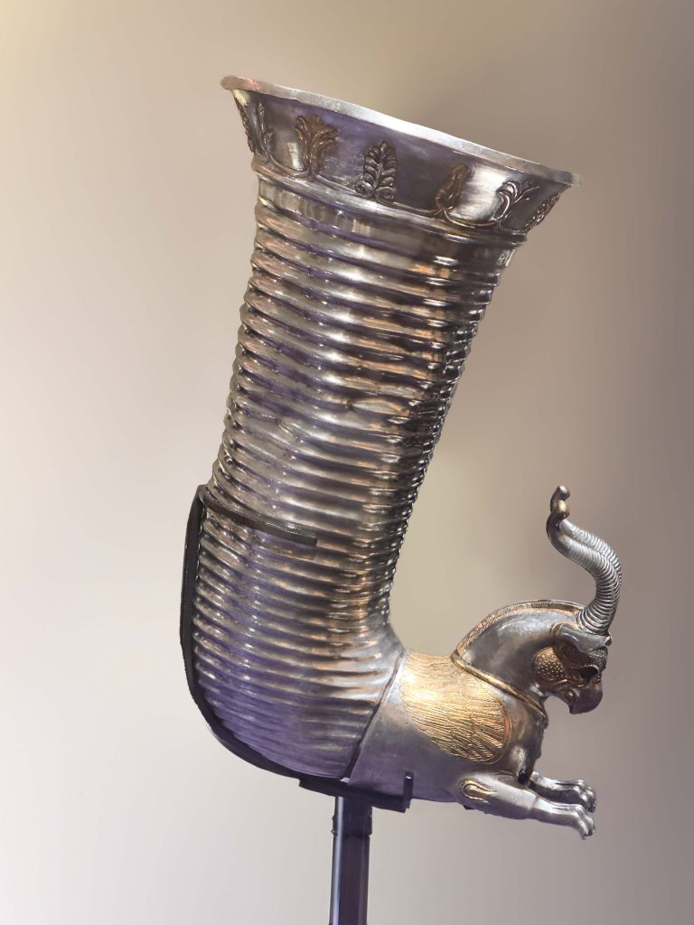 Achaemenid gilt silver rhyton showcasing a horned winged griffin, palmettes, and lotus-buds detailing, representing the elegance of Persian drinks.
