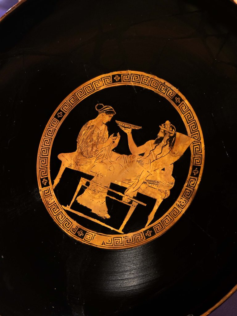 A detailed Greek relief from the 4th - 3rd century BC depicting the divine symbolism of Persian drinking vessels, illustrating the merging realms of mortals and gods, and the intertwined destinies of Greek and Persian cultures.