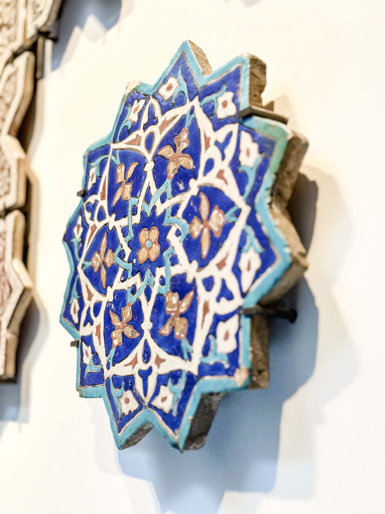 15th-century Timurid cuerda seca star tile with stylized peonies in cobalt blue, black, red, white, and gold, exhibited at the British Museum. Persian Tile Artistry