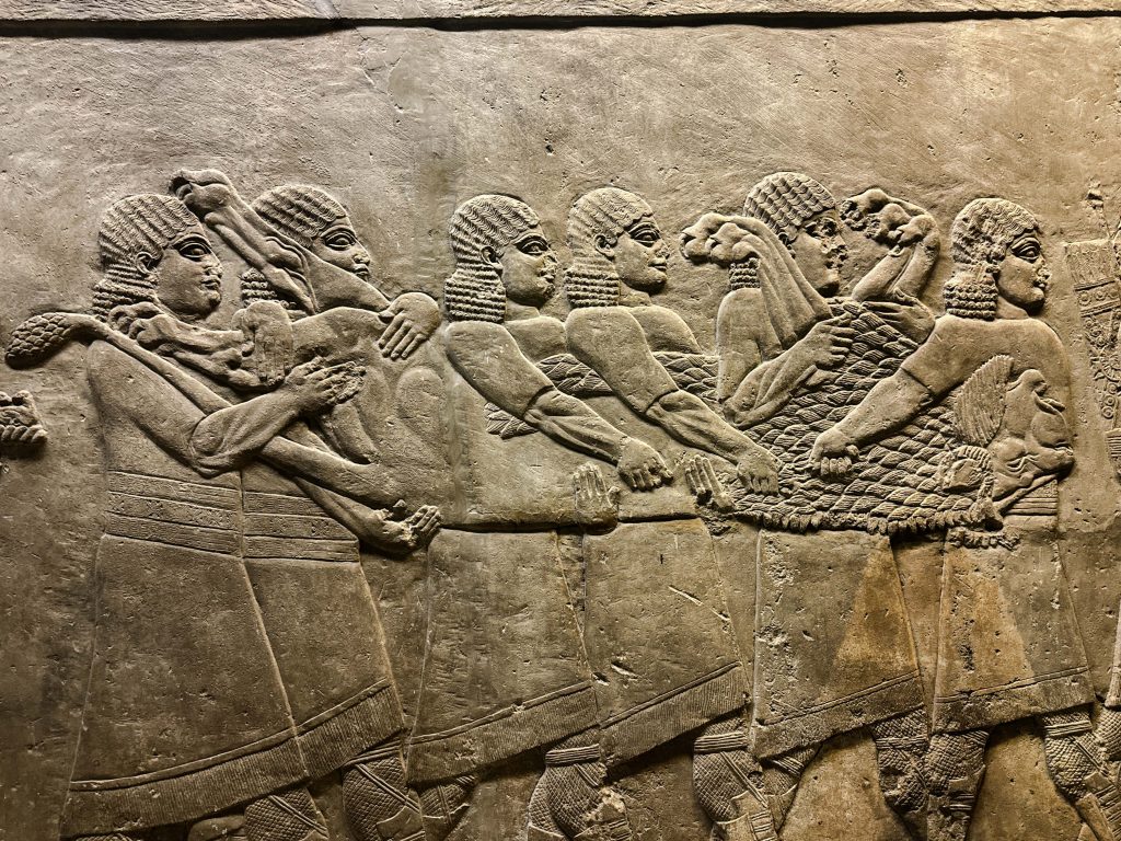 Gypsum wall panel relief from the Neo-Assyrian period, portraying men carrying a defeated Persian lion with a bowman in tow, symbolizing Ashurbanipal's triumphant return from the hunt.