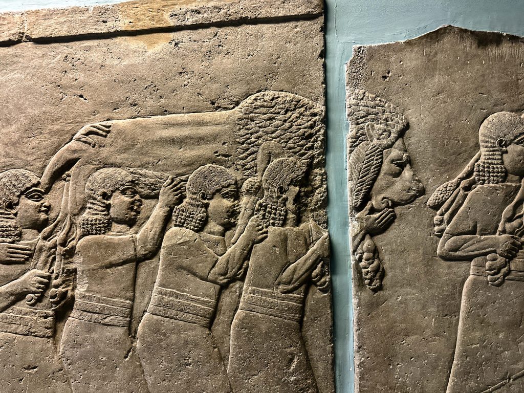 Gypsum wall panel relief from the Neo-Assyrian period, portraying men carrying a defeated Persian lion with a bowman in tow, symbolizing Ashurbanipal's triumphant return from the hunt.